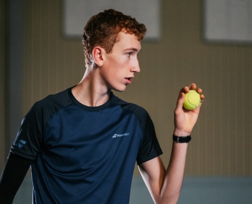 tennis player holding the ball looking focused