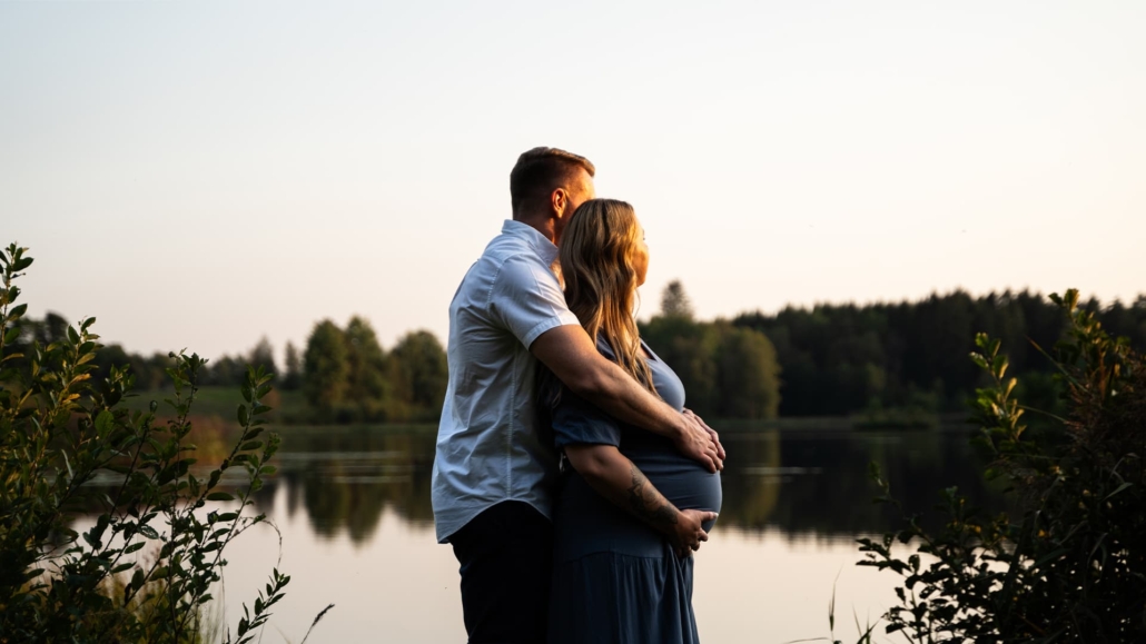man and pregnant woman overlooking a small lake