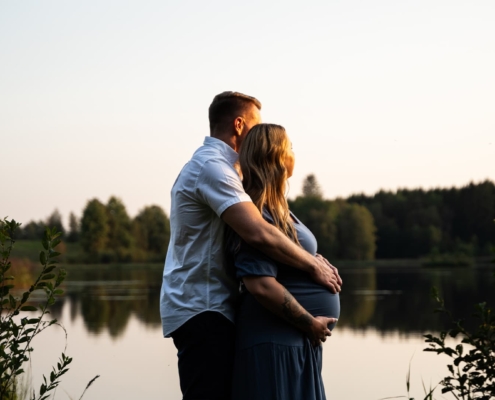 man and pregnant woman overlooking a small lake