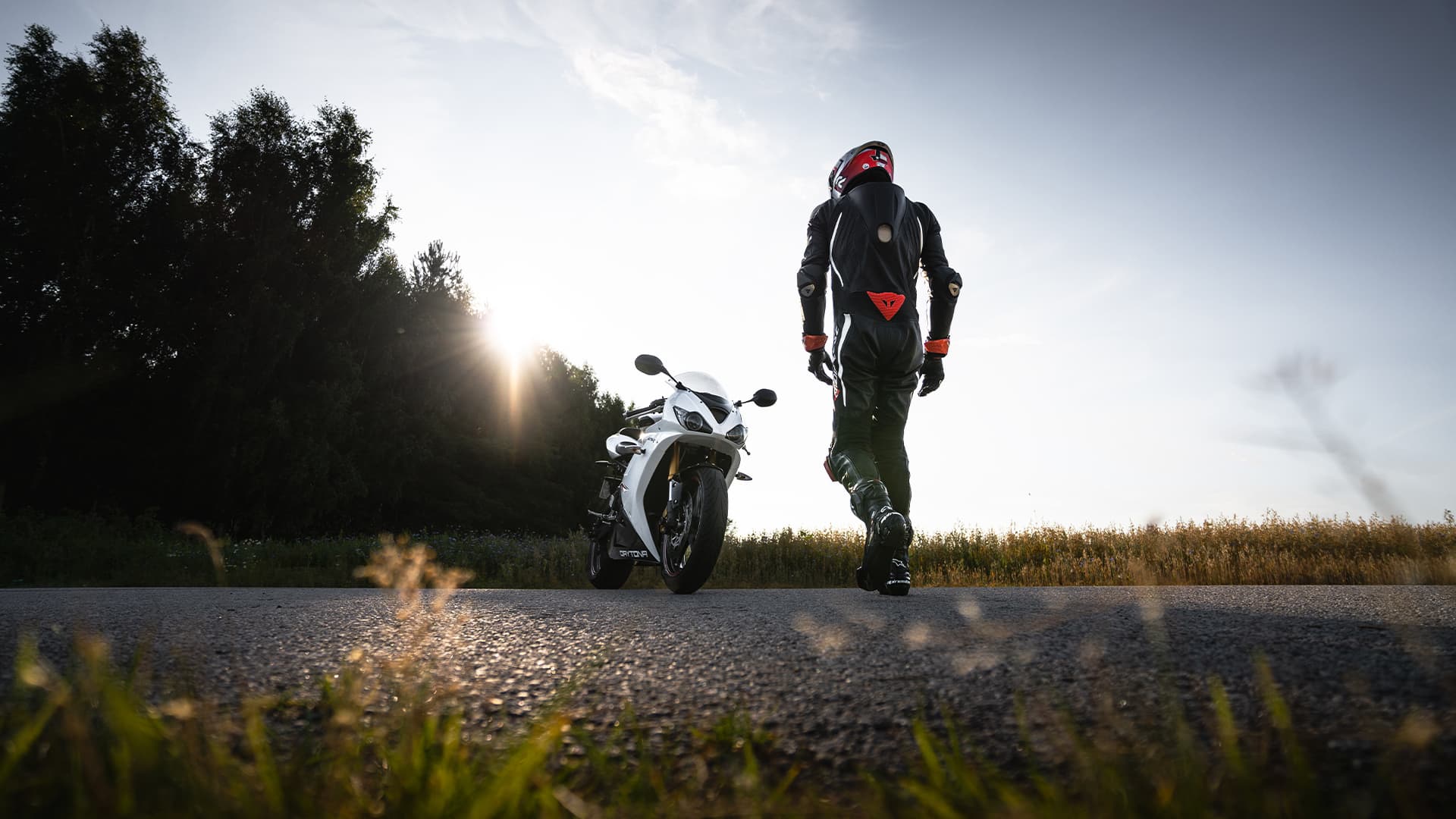 Person walking towards a sportbike during sunset