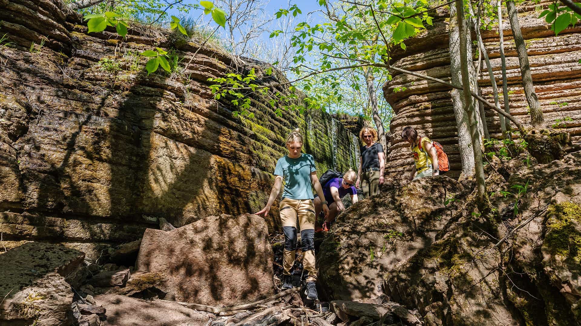 People climbing down a tiny waterfall at Kinnekulle