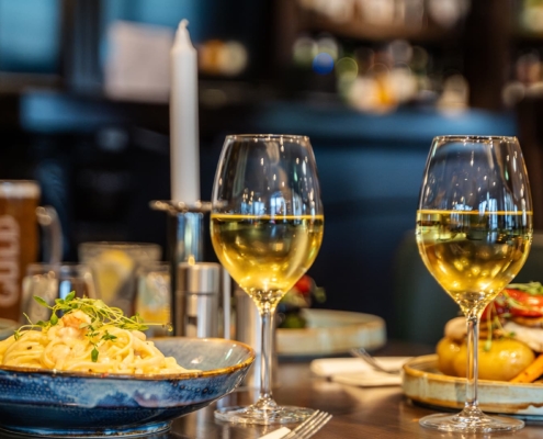 close up of two glasses of wine and food in a restaurant