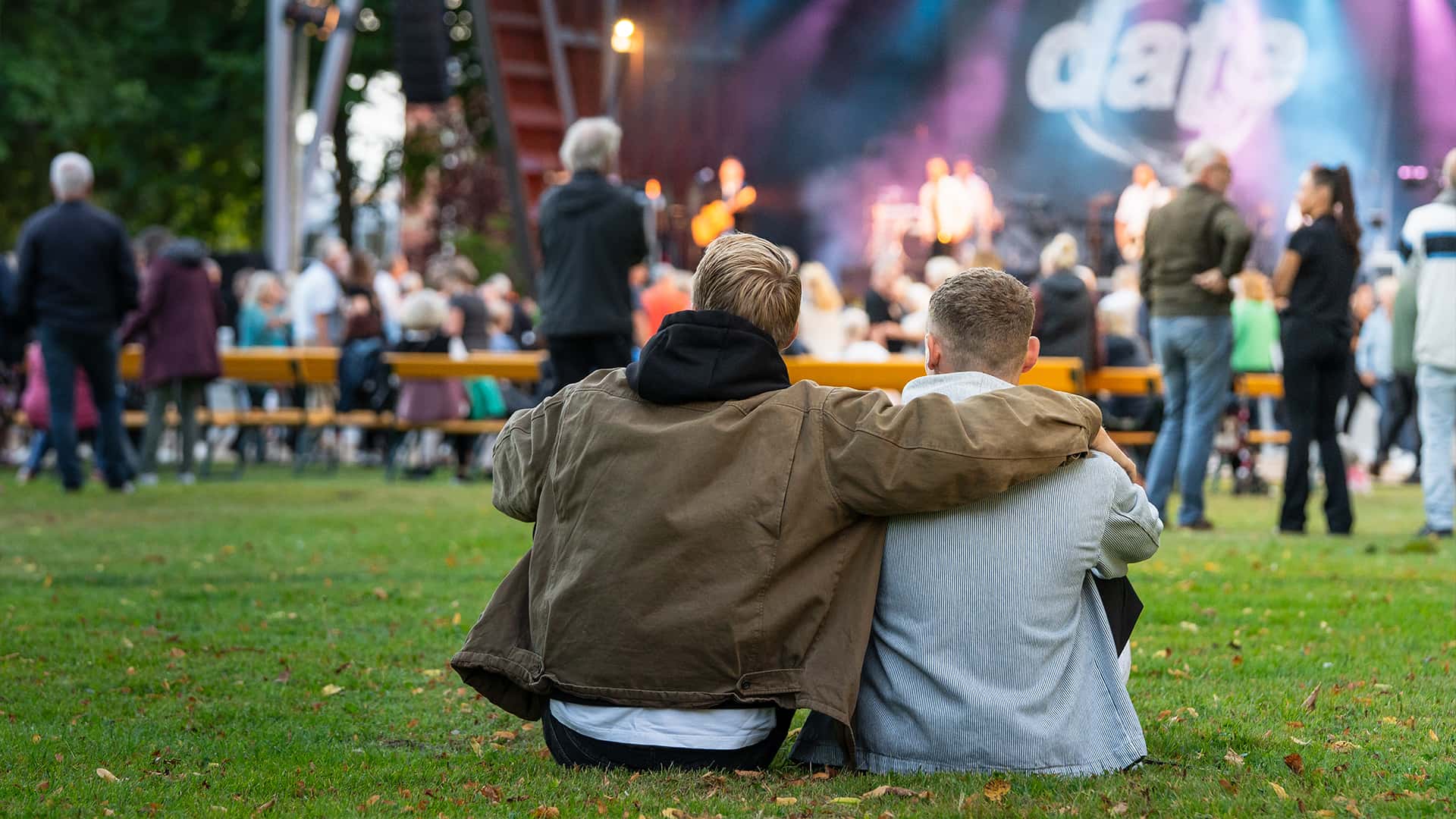 two friends sitting on the grass at a concert