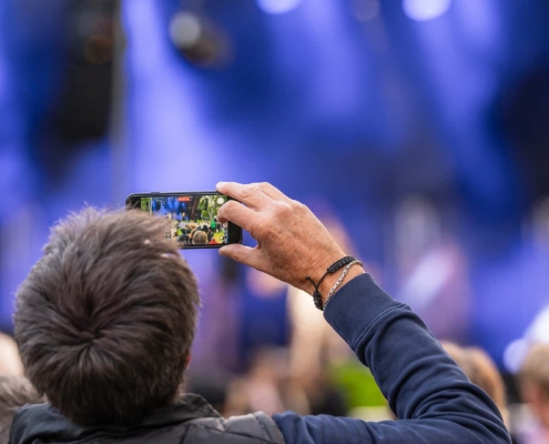 a guy filming a concert with his phone in focus
