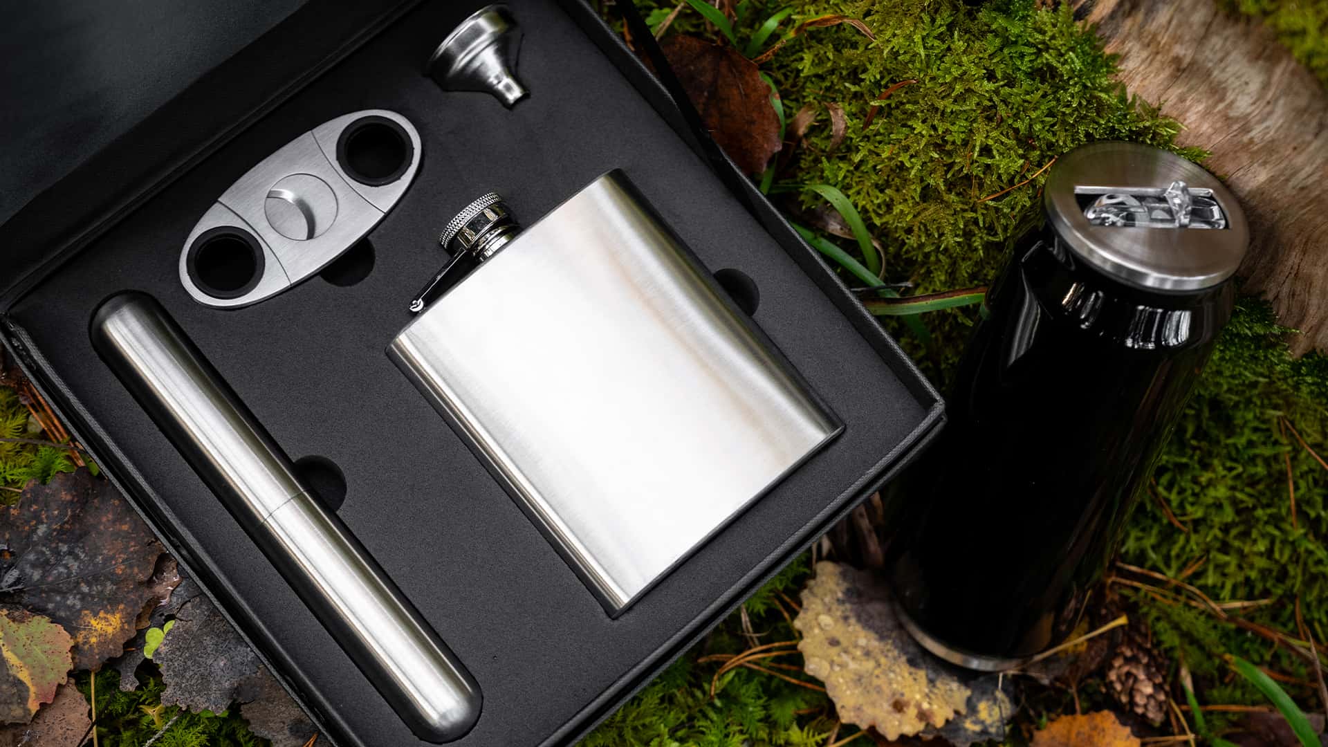 close up of a pocket flask in silver with accessories in a case shot in the forest