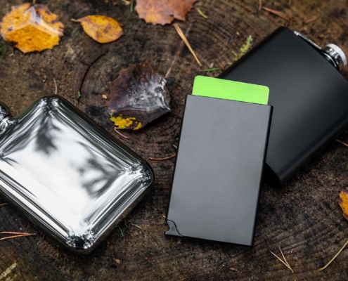 close up of a card holder with pocket flask besides it shot in a forest