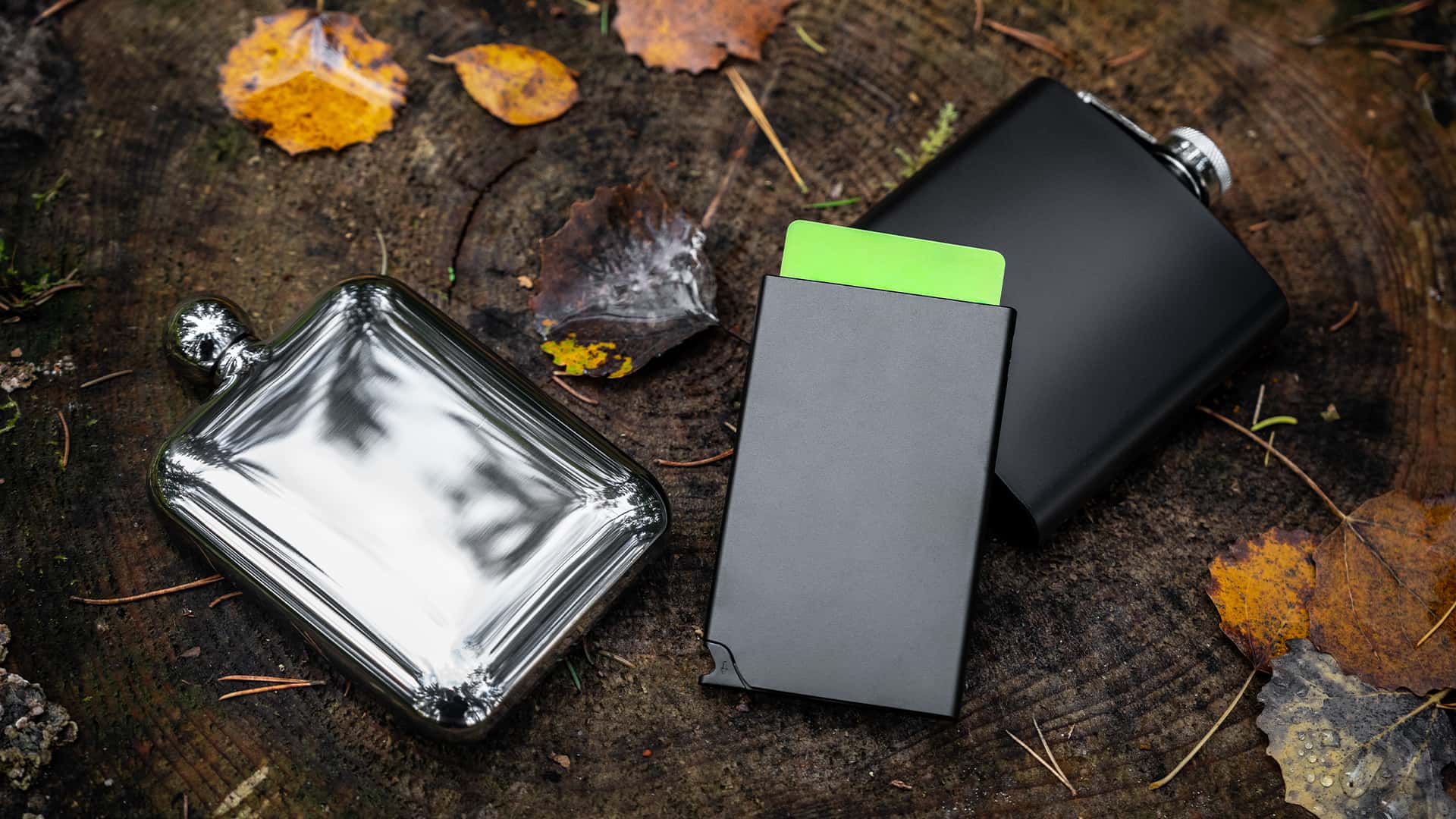 close up of a card holder with pocket flask besides it shot in a forest