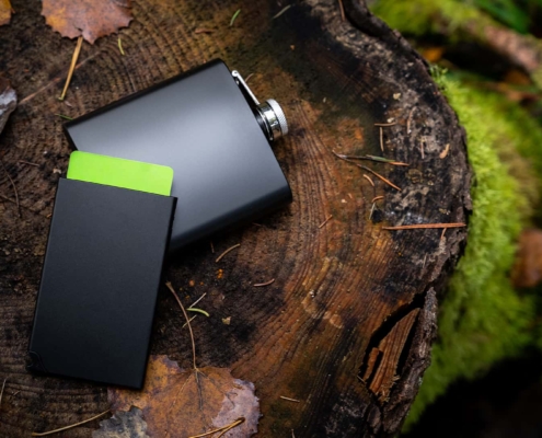 close up of a card holder with pocket flask besides it shot in a forest