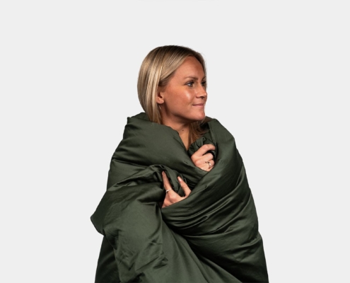 woman model being tucked into a duvet in a studio
