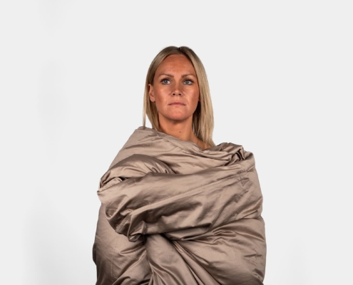 woman model being tucked into a duvet in a studio