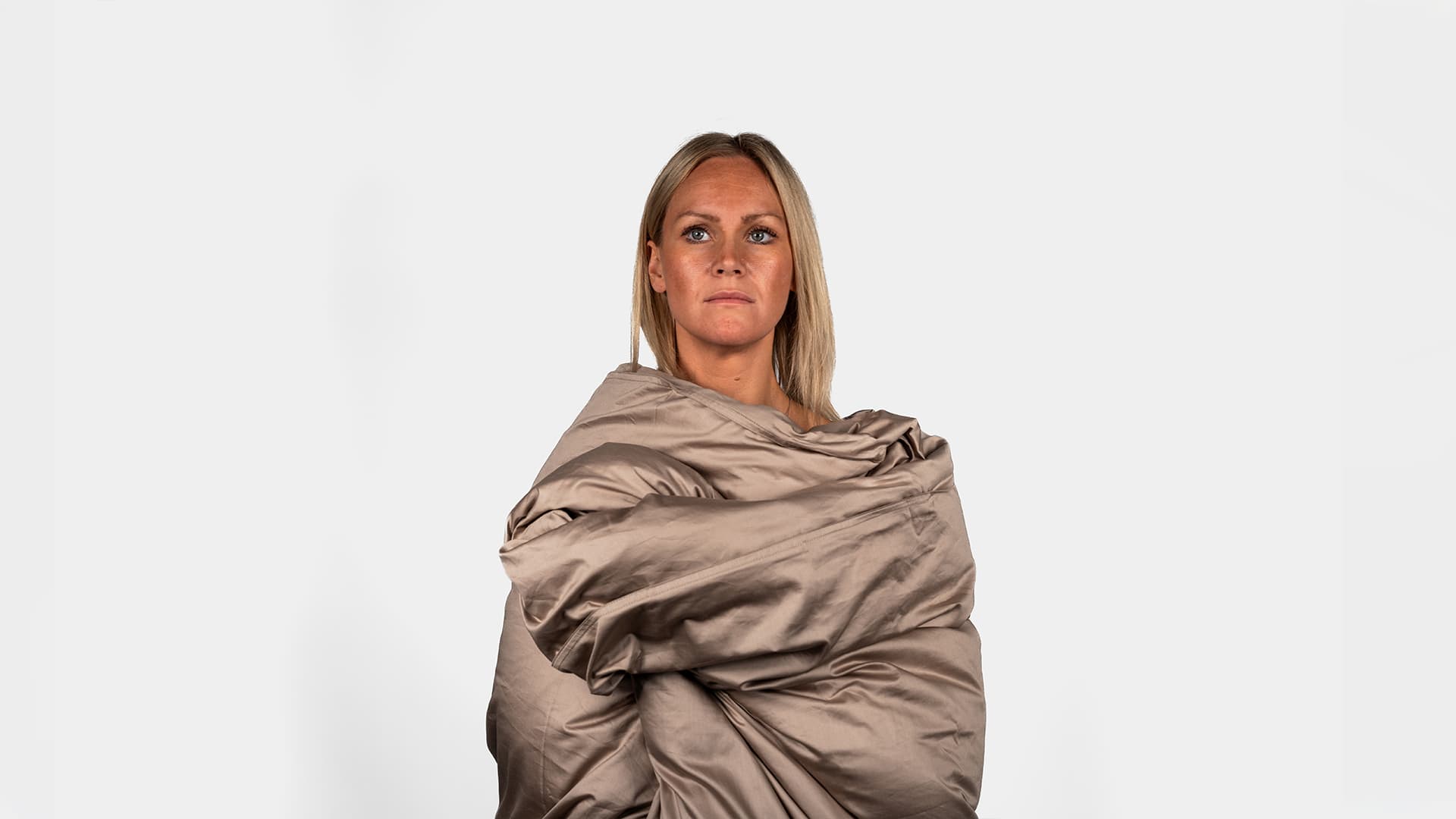 woman model being tucked into a duvet in a studio