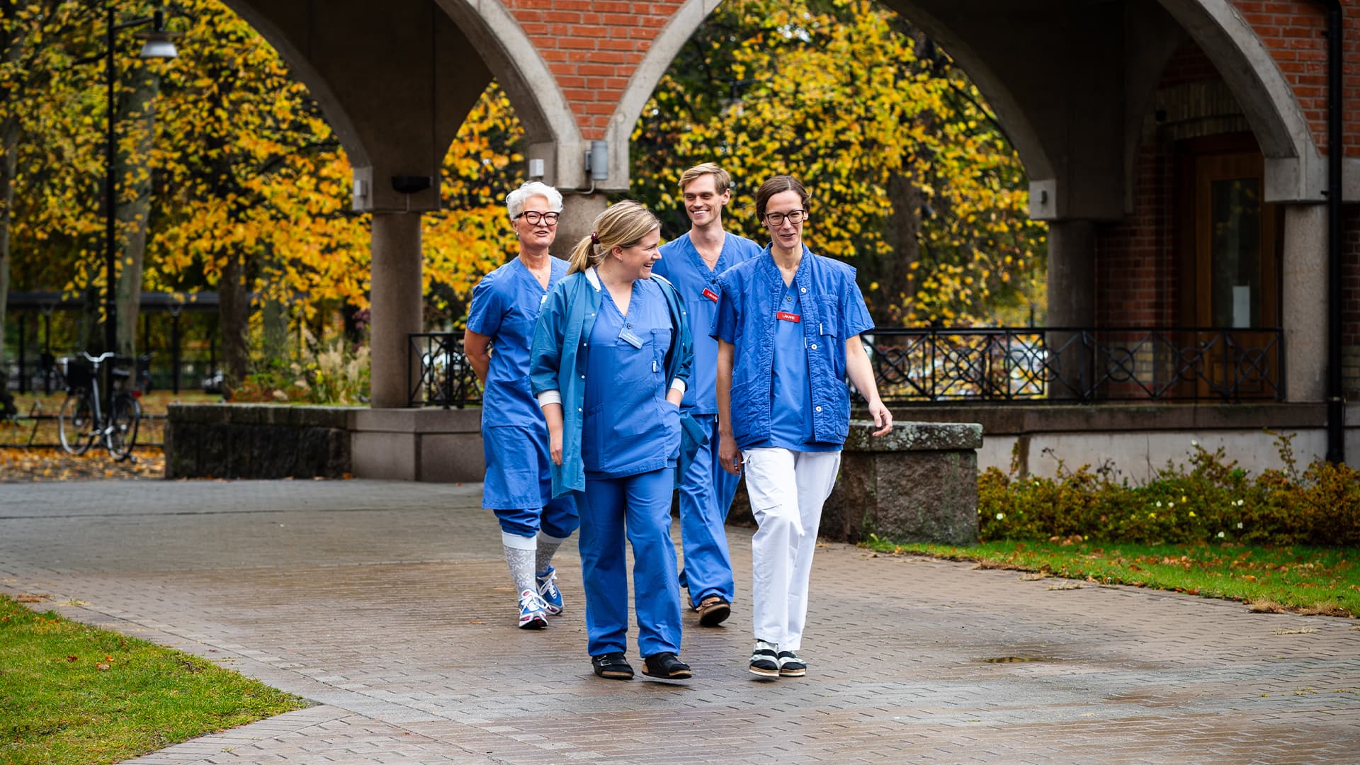 Healthcare personnel walking outside of the hospital during an autumn day