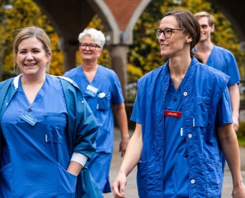 Healthcare personnel walking outside of the hospital during an autumn day
